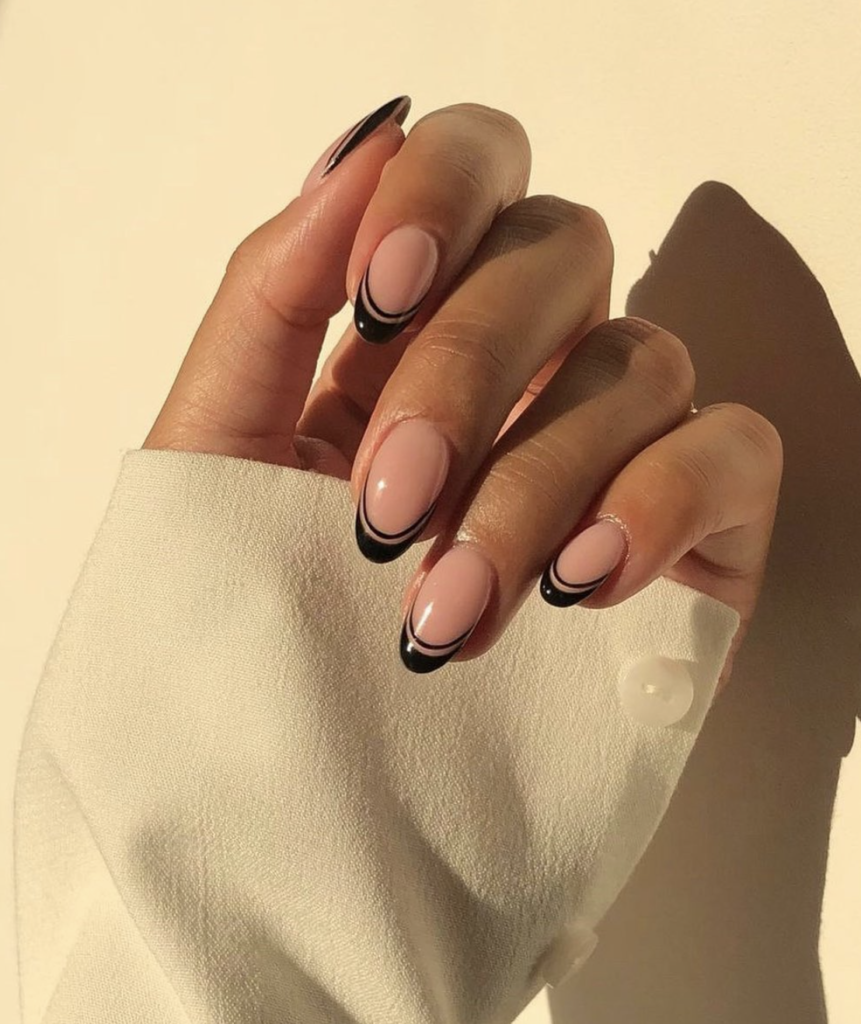 Close-up of nails with black double French tips on a nude base.
